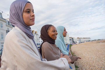 Three Muslim woman looking away while standing on beach