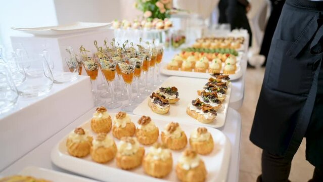The waiter places the finished sandwiches on the table with treats. Catering.