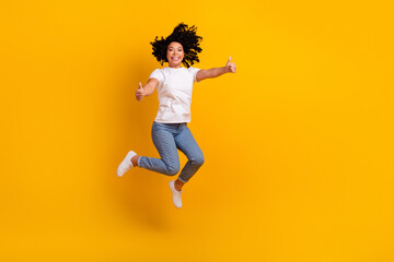 Fototapeta na wymiar Full length photo of confident pretty lady dressed white t-shirt showing thumbs up jumping high empty space isolated yellow color background