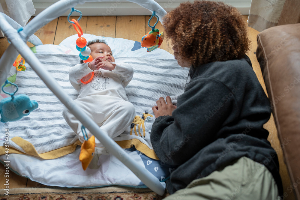 Canvas Prints Mother looking at baby daughter lying on play mat at home