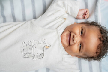 Smiling baby girl with curly hair and brown eyes - obrazy, fototapety, plakaty