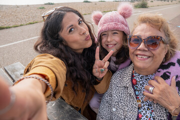 Grandmother, mother and daughter taking selfie on beach