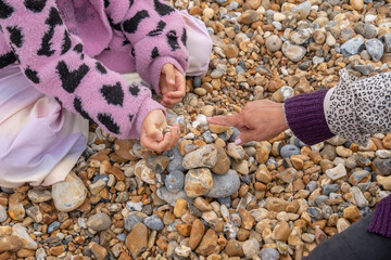 Grandmother and granddaughter playing with stones on beach