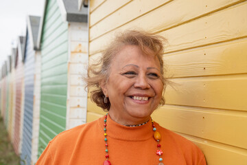 Portrait of smiling senior woman standing by beach hut