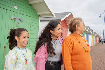 Grandmother, mother and granddaughter standing by beach hut