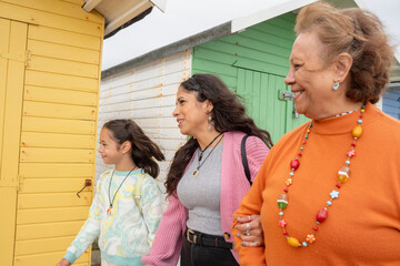 Grandmother, mother and granddaughter walking by beach hut