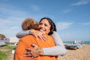 Mother and daughter embracing on beach on sunny day