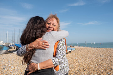 Mother and daughter embracing on beach on sunny day
