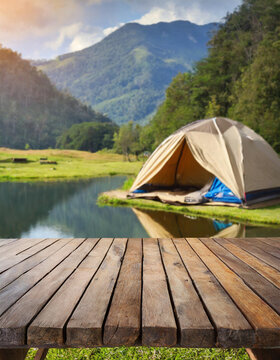 Wooden table in the blur camping tent at sunset in the mountain near the lake. Cool and relaxing concept. For product display montage or key visual layout design. space for text