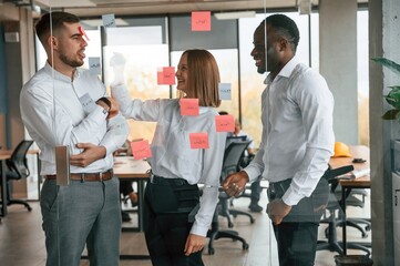 Fototapeta premium Stickers on the glass, planning the project. Group of office workers are together indoors