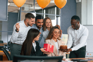 Celebration with cake, balloons and gift box. Employee having a birthday in the office, group of...