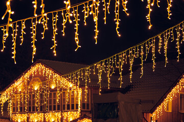Flickering lights of hanging garlands for New Year christmas street decorations at night, merry...