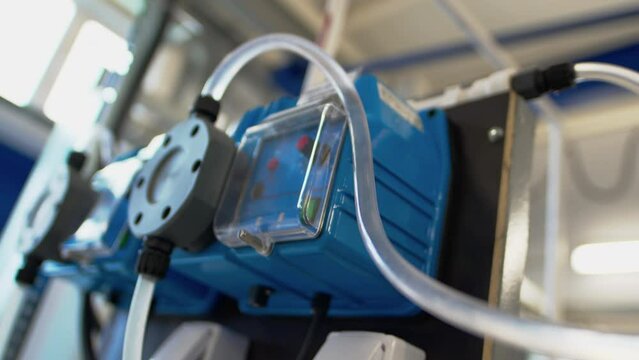 Flocculant dosing pump with plastic pipes and sockets in plant workshop closeup. Equipment of contemporary wastewater treatment facility
