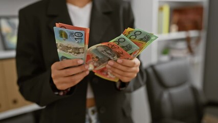 A young asian businesswoman in an office holds australian dollars, illustrating financial concepts.