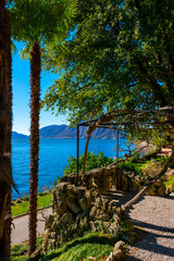 Fototapeta na wymiar Balcony on Lake Lugano with Mountain and Palm Tree in a Sunny Day with Clear Sky in Lugano, Ticino, Switzerland.