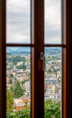 Window View with Cityscape and Mountain and in a Cloudy Day in Ticino, Switzerland.