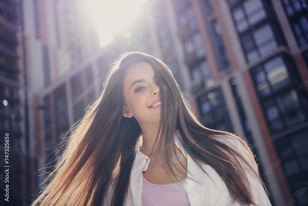 Wall mural Photo of positive pretty girl toothy smile flying hair enjoy morning sunlight city center buildings outside