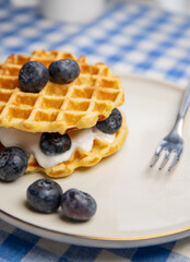 Delicious breakfast featuring Belgian waffles with blueberries, natural yogurt. dessert fork. apple healthy waffles