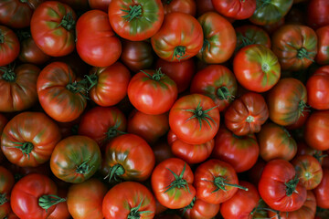 Clean eating concept. Bunch of ripe juicy freshly picked organic heirloom tomatoes at local produce farmers market stand. Close up, background, copy space.