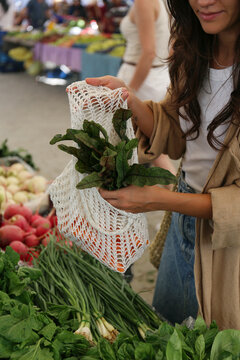 Young woman choosing fruits, vegetables, herbs and greens from a stand on farmers market. Shopping for organic local produce. Close up, copy space, background.