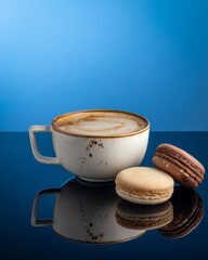 cappuccino mug with macaroon on blue background