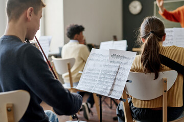 Selective focus shot of group of teenagers playing instrumental music in school orchestra at class © AnnaStills