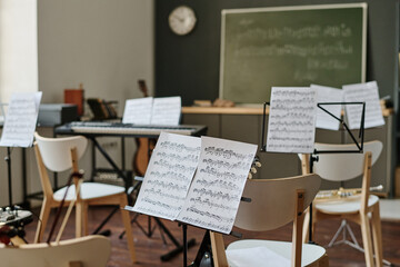 Selective focus no people shot of sheet music on music stands in modern classroom interior, copy...