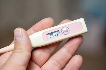 Checking temperature at home with digital thermometer, high body temperature, fever, high-Grade...