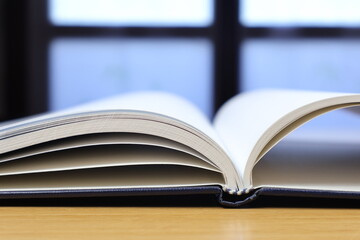 Isolated notepad on the desk and close-up with blank sheets in front of the window.