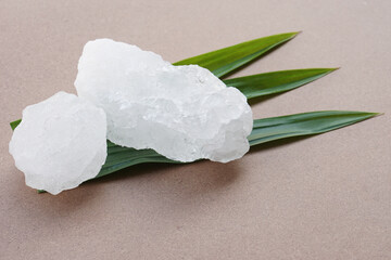 White crystal alum stones or Potassium alum on green leaves. Chemical compound. Useful for beauty...