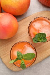 Tasty freshly made grapefruit juice, fruits and mint on light grey table, top view