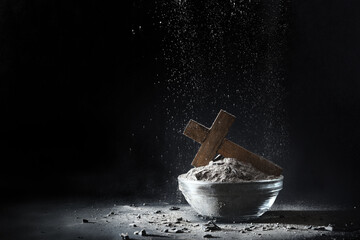Ashes falling on fly with Christian cross and dark background