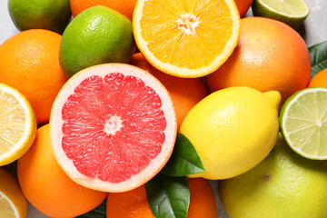 Pile of different fresh citrus fruits and leaves on table, above view