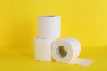 Many soft toilet paper rolls on yellow background