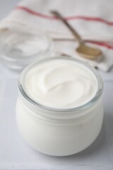 Delicious natural yogurt in glass jar on white table, closeup