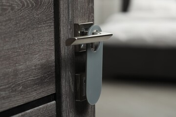 Wooden door with blank hanger on metal handle, closeup
