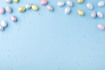 Festive Easter background. Multicoloured Easter eggs on a blue table. Banner with a place for text. Top view.