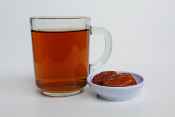 Three pieces of Deglet noor or deglet nour or date palm or dates, with a glass of tea, isolated on white background