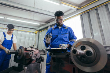 Diversity mechanic worker or metalworker using metal lathe machine operate polishing car disc brake at auto repair garage. Maintenance automotive and inspecting vehicle part concept