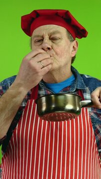 Senior gourmet chef smelling food aroma from stewpan enjoying of smell of food.