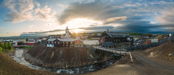 Super panorama of evening sun casts a warm glow over Roros, Norway, highlighting the town's heritage architecture and the rugged beauty of its mining landscape from above