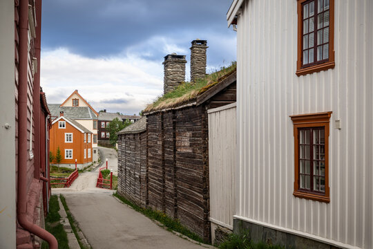 Nestled within the historic village of Roros, this street view captures the unique charm of timber walls and sod roofs, with a pop of color from traditional Norwegian houses