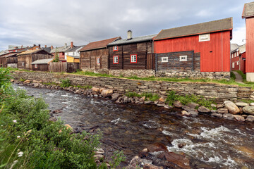 Fototapeta na wymiar The heritage-rich landscape of Roros unfolds along the Glomma River, featuring traditional timber homes with red accents