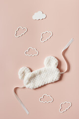 Sleeping mask from light fur and clouds shape on pale pink background. Still life details, cozy...