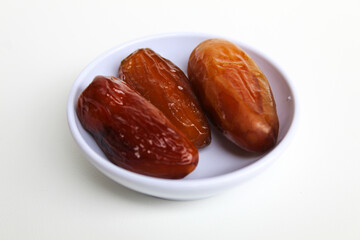 Three pieces of Deglet noor or deglet nour or date palm or dates, in a small bowl, isolated on...