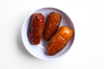 Three pieces of Deglet noor or deglet nour or date palm or dates, in a small bowl, isolated on white background, flat lay or top view