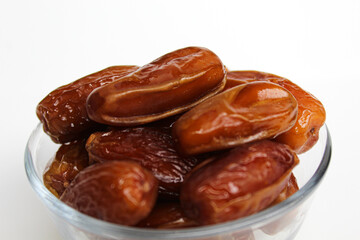 Deglet noor or deglet nour or date palm or dates, in a transparent bowl, isolated on white background