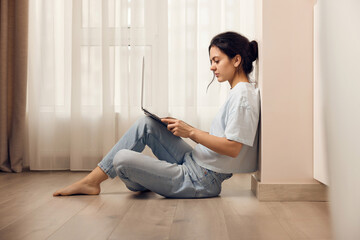 casual woman sitting on the floor and working on laptop at home