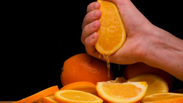 Squeezing out the fresh orange. A picture of a person's hand squeezing orange juice. Hand squeezing half fresh oranges on the orange press with pulp. hand holding fresh raw citrus.