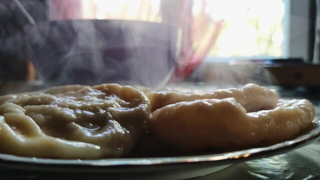 Delicious plate of hot dumplings also known as varenik with steam rising above it. Macro footage of hot traditional dish on table prepared for having breakfast in the countryside. Stuffed dough treats